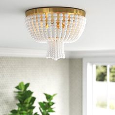 a chandelier hanging from the ceiling in a living room with potted plants