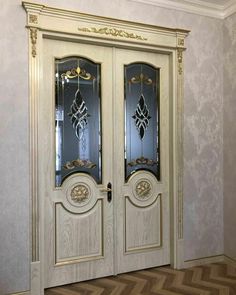 an ornately decorated double door in a room with parquet flooring and wallpaper