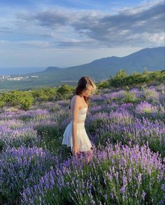 a woman standing in a field of purple flowers