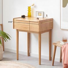 a small wooden table with two drawers and a plant on the floor next to it