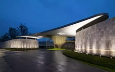 the entrance to a modern building lit up at night with lights shining on it's sides