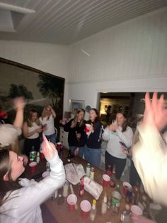 a group of people standing around each other at a table with drinks in front of them