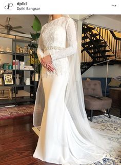 a woman in a white wedding dress standing on a wooden floor with a long veil over her head