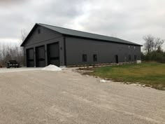 a large black barn sitting on the side of a road