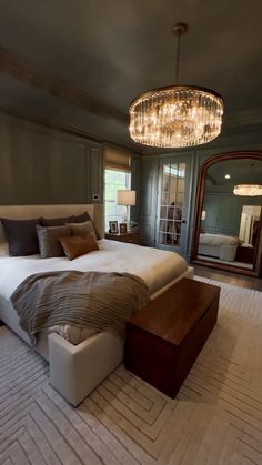 a bedroom with a large bed and chandelier in the corner, along with a mirror on the wall