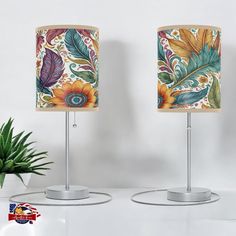 two lamps with floral designs on them next to a potted plant