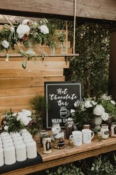 a wooden table topped with lots of white flowers and jars filled with different types of items