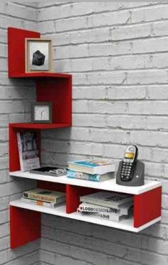 a red and white shelving unit with a phone on it's shelf next to a brick wall