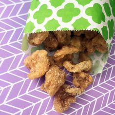 a bag filled with fried food sitting on top of a purple and white tablecloth