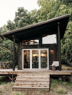 a small wooden cabin sitting on top of a grass covered field next to a forest