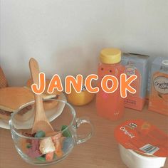 a wooden table topped with lots of food and drinks next to a jar of jam