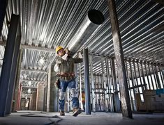 a construction worker is walking through a building with steel pipes on the ceiling and walls