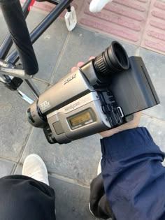 a person holding a video camera on top of a bike handlebars and seat