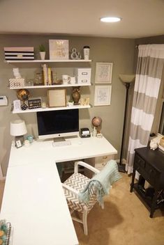 a desk with a computer on top of it in front of a curtained window