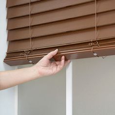 a hand is holding onto the blinds that are closed