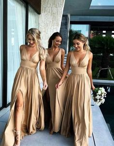 three beautiful women in long dresses walking down the street with one holding her hand out