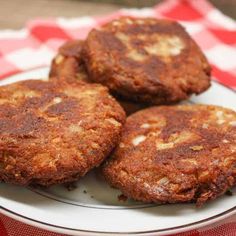 three fried patties on a plate sitting on a red and white checkered tablecloth