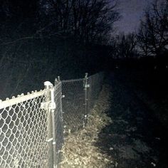 a chain link fence is lit up at night