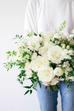 a woman holding a bouquet of white flowers