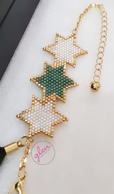 a cross stitch bracelet with bells attached to it's sides, on a white surface