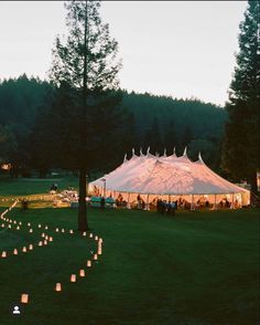 a large tent set up with candles in the grass