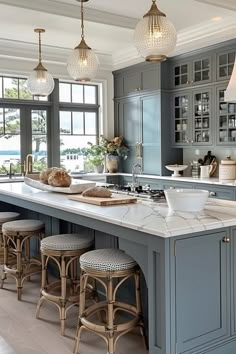 a large kitchen with blue cabinets and marble counter tops, along with bar stools