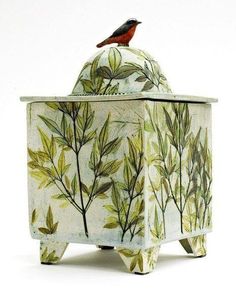 a bird is sitting on top of a planter that has leaves painted on it