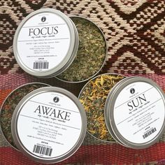 four tins filled with different types of tea sitting on top of a rug next to each other