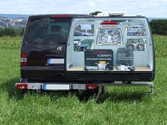 the back end of a van parked on top of a lush green field