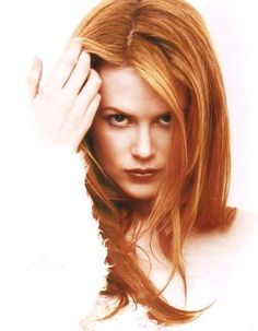 a woman with long red hair is posing for the camera and has her hand on her head