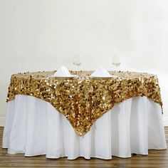 a table with gold sequins on it and two wine glasses at the top