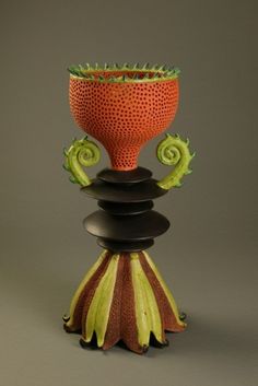 a red vase sitting on top of a black stand