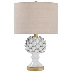 a white lamp with a beige shade on the base and a gold trim around it