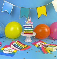 a birthday cake surrounded by balloons and confetti on a blue table with streamers