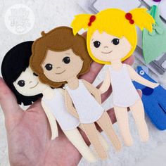 three felt dolls are held in the palm of someone's hand, one is wearing a white dress