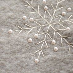 a snowflake made out of white pearls on top of a gray surface with other beads