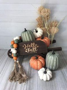 pumpkins and gourds are arranged in a wagon with the word hello fall painted on it