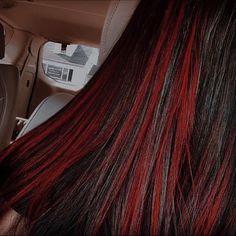 the back of a woman's head with red and black hair in a car