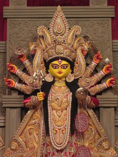 an elaborately decorated statue is displayed in front of a red and gold wallpaper