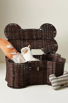 an open wicker trunk with stuffed animals in it on a white table next to pillows