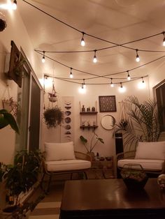 a living room filled with furniture and lots of lights hanging from the ceiling above it