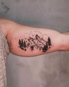 a man's arm with trees and mountains on it