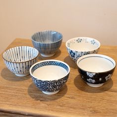 four blue and white bowls sitting on top of a wooden table next to each other