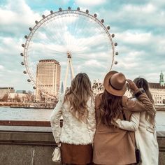 two women standing next to each other looking at the ferris wheel in front of them