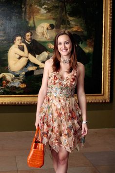 a woman standing in front of a painting holding a purse