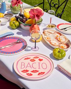 the table is set with plates, glasses and fruit for an elegant dinner in the garden