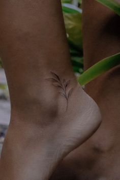 a woman's foot with a small flower tattoo on the side of her ankle