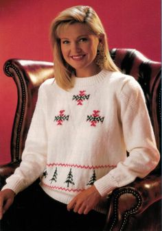 a woman sitting in a chair wearing a white sweater with christmas trees on the front