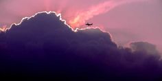 an airplane is flying through the clouds at sunset