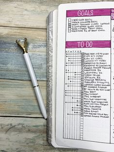 an open planner and pen sitting on top of a wooden table